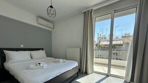 Een moderne hotelkamer met een groot bed, een radiator en uitzicht op de stad door een schuifdeur.