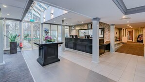 A spacious lobby with a reception desk, large windows, and a fire extinguisher. - The Landmark Hotel and Leisure Club | SUPR DBL (Dundee)