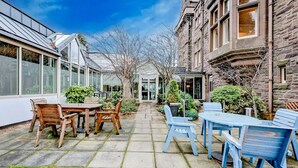 A courtyard with a table and chairs, a glass conservatory, and a stone building. - The Landmark Hotel and Leisure Club | SUPR DBL (Dundee)