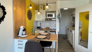 Una cucina moderna con un piano di lavoro in legno, mobili bianchi e un'area pranzo con un tavolo apparecchiato per due.