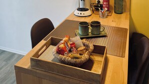 Un'area pranzo con un tavolo in legno, due lampade a sospensione, una macchina da caffè e uno specchio decorativo al muro.