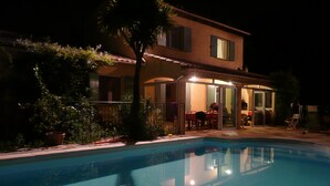 Una casa con piscina, un patio cubierto y un jardín.