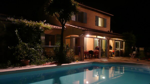 A house with a swimming pool, a covered patio, and a garden.