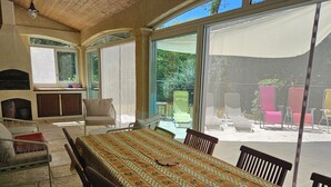 Un patio iluminado por el sol con una mesa de comedor, sillas y zona de barbacoa.
