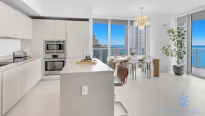 Una cocina moderna con una isla central, un comedor con vistas y una gran planta en maceta.