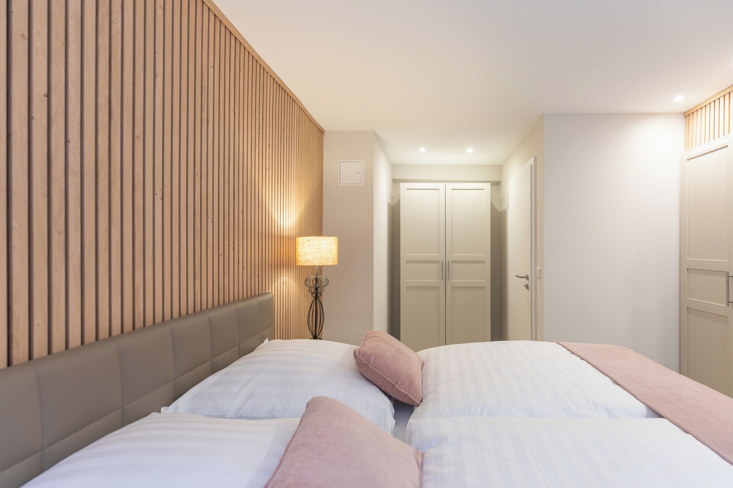 A hotel room with a bed, a bedside lamp, and a wooden panel wall.