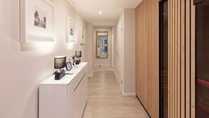 Een gang met ingelijste foto’s aan de muur, een bureau met lamp en klok, en een houten paneelwand.