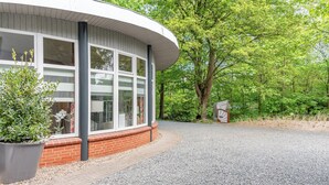 Een modern gebouw met grote ramen en een gebogen dak, omgeven door weelderige begroeiing.