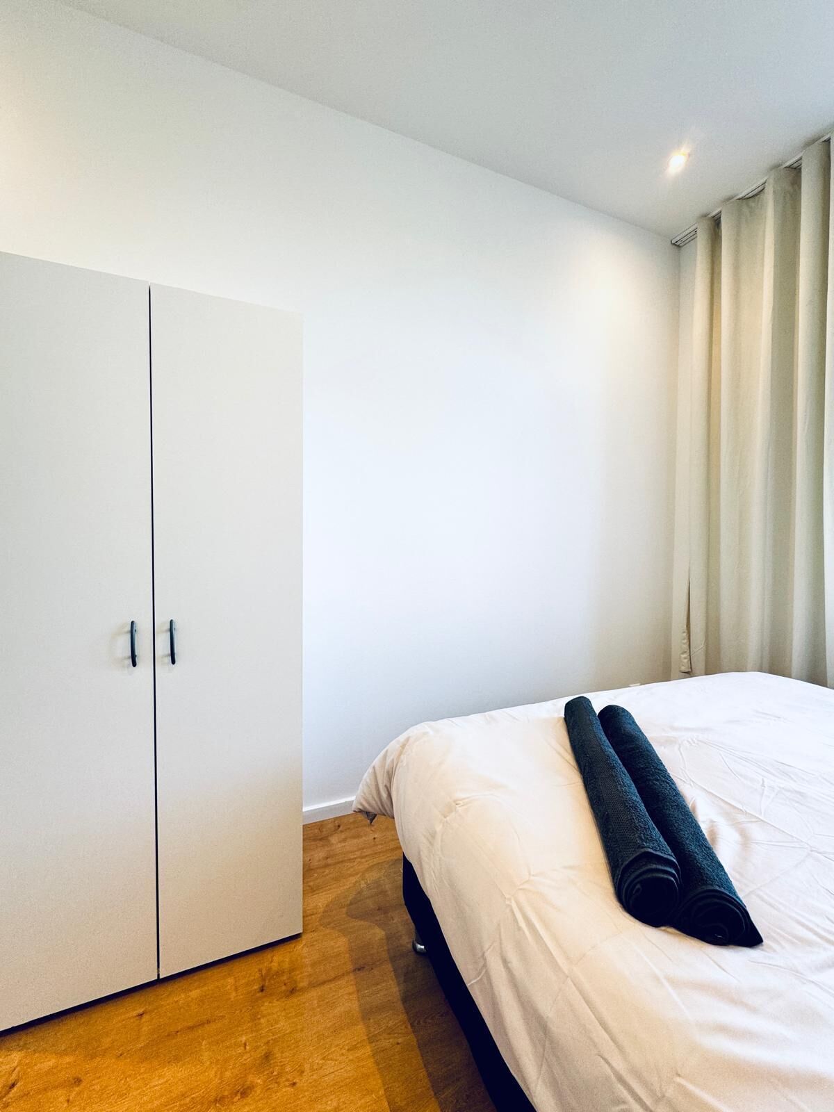 Un dormitorio con cama, armario y cortina.