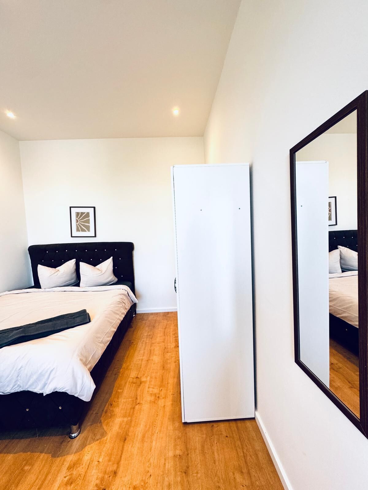 Un dormitorio con una cama, un armario y un espejo.