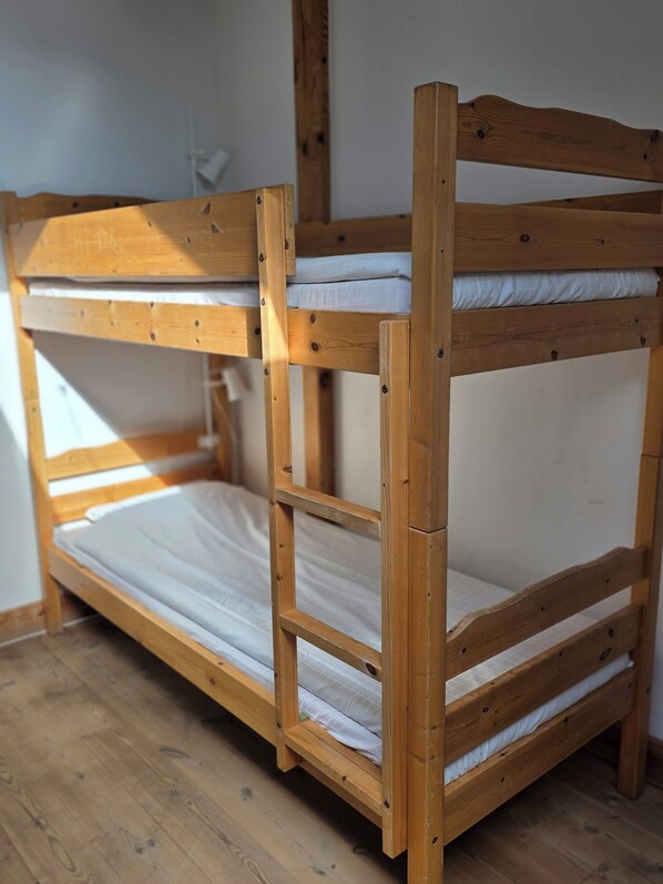 A bunk bed with a wooden frame and white bedding. - Siaröfortet (Ljustero)