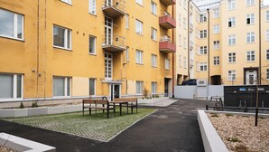 Ein Innenhof mit gepflastertem Weg, Bänken und einem kleinen Garten.