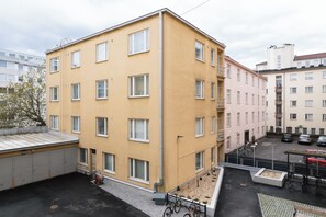 A multi-story building with a flat roof, large windows, and a parking area with cars and bicycles. - Comfy Studio in Central Helsinki (Helsinki)