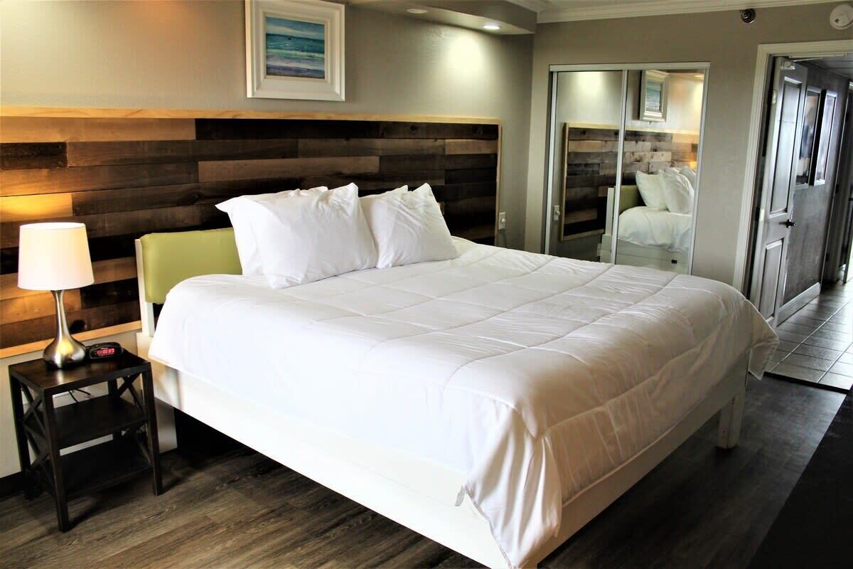 A neatly made bed with white bedding, a bedside lamp, and a wooden headboard.