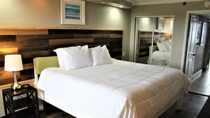 Una cama bien hecha con ropa blanca, una lámpara de noche y un cabecero de madera.