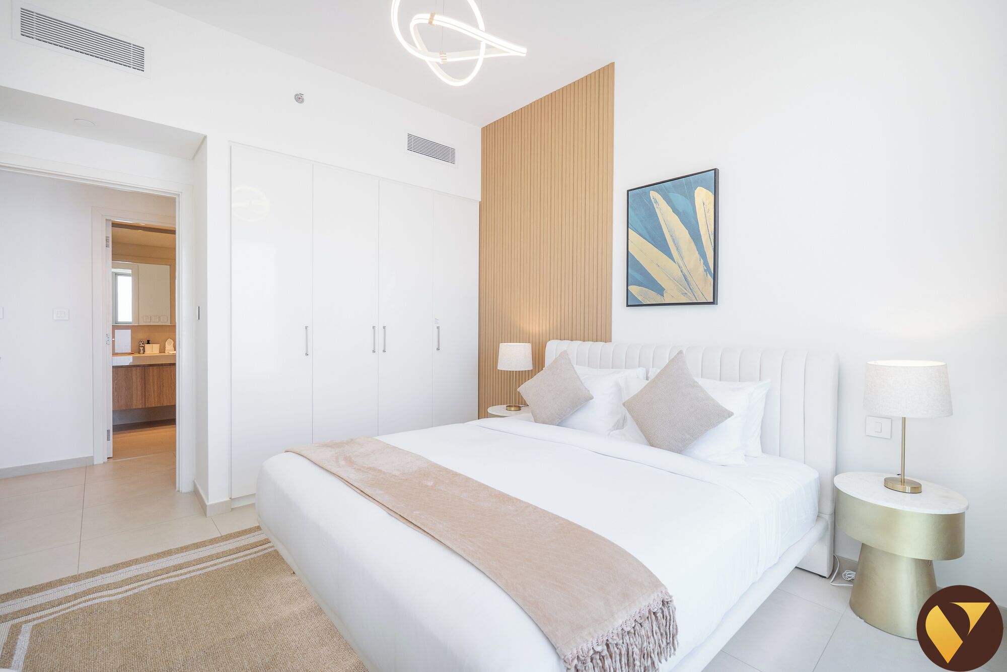 A modern bedroom with a large bed, bedside lamps, a wooden panel wall, and a painting.