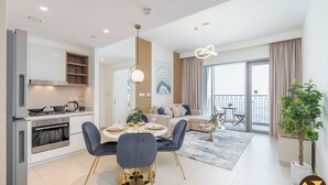 A modern apartment with a kitchen, dining area, living room, and balcony. - Vogue | Downtown with Direct Access to Dubai Mall (Dubai)