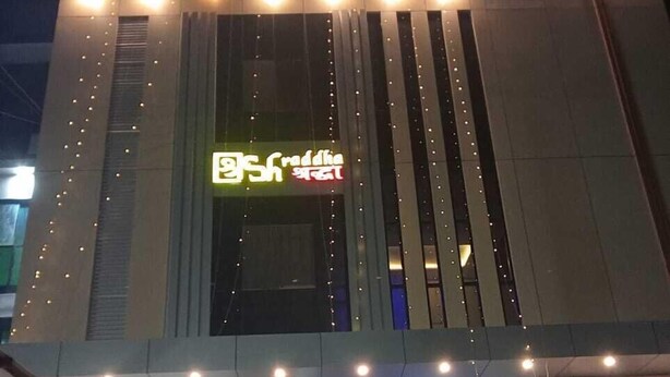 Een gebouw met een modern ontwerp, met een opvallend bord met tekst in een niet-Latijns schrift, een trap die naar de ingang leidt, en een reeks lampen langs de gevel.