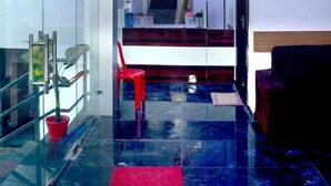 Een moderne hotel lobby met een glazen scheiding, een rode stoel, een trap en een rood tapijt.
