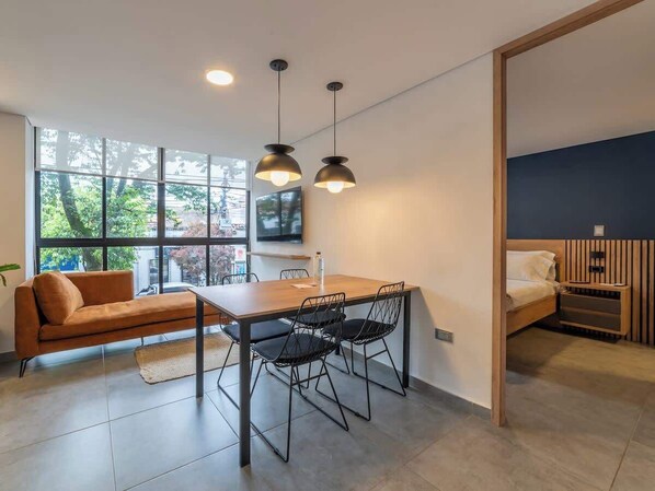 A modern room with a dining table, chairs, a sofa, and a bed.