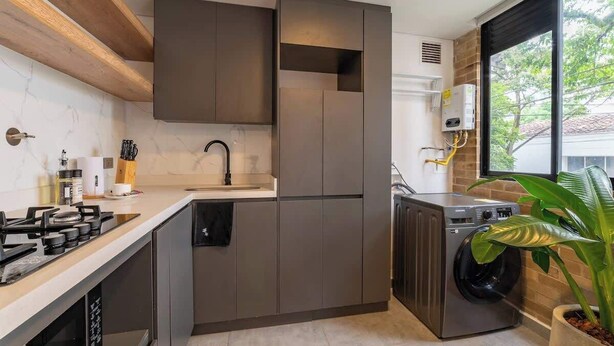 A modern kitchen with built-in appliances, a dishwasher, and a large window providing natural light. - w* | Welcoming 2BR in Laureles w/ City View (Medellín)
