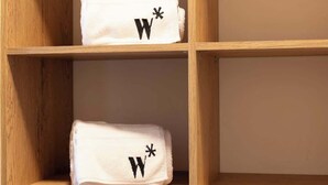 Two white towels with black 'W*' symbols on a wooden shelf. - w* | Welcoming 2BR in Laureles w/ City View (Medellín)