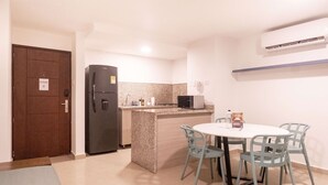 A compact kitchen with a refrigerator, microwave, and a small island with chairs. - w*| Glorious 2BR w/ AC in Bocagrande (Cartagena de Indias)
