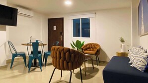 A modern living room with a sofa, two armchairs, a coffee table, and a TV mounted on the wall. - w*| Breathtaking 2BR w/ AC in Bocagrande (Cartagena de Indias)