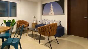 A modern living room with a dining area, featuring a sofa set, chairs, a coffee table, and a painting of a tower. - w*| Breathtaking 2BR w/ AC in Bocagrande (Cartagena de Indias)
