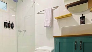 A bathroom with a glass-enclosed shower, a white toilet, a teal cabinet, and a mirror above the sink. - w*| Breathtaking 2BR w/ AC in Bocagrande (Cartagena de Indias)