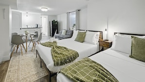 A hotel room with two beds, a dining area, and a kitchenette.