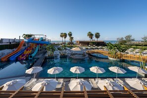 A resort pool with water slides, lounge chairs, umbrellas, and palm trees. - Sentido Luna Vista Belek Hotel (Serik)