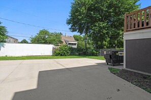 A residential driveway with a concrete surface, a white fence, and a large tree. - Mini Streetcar Central - Near Westport/Plaza (Kansas City)
