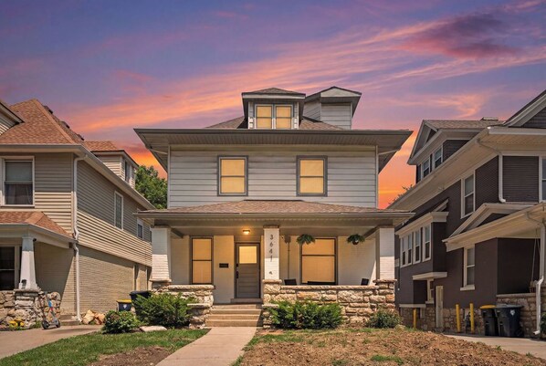 A two-story house with a front porch, stone foundation, and a number '364' sign.