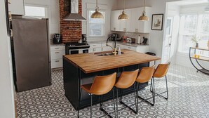 Una cucina moderna con isola centrale, sgabelli da bar e luci a sospensione.