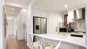 A modern kitchen with white cabinetry, a stainless steel refrigerator, a microwave, and a stove.