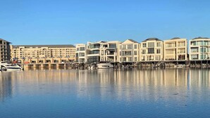 A waterfront hotel with modern architecture, a marina, and a clear blue sky.