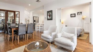 A modern living room with a dining area, a sofa, and a bed.
