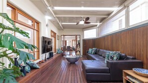 A spacious living area with a wooden floor, a sofa, a coffee table, and a television.