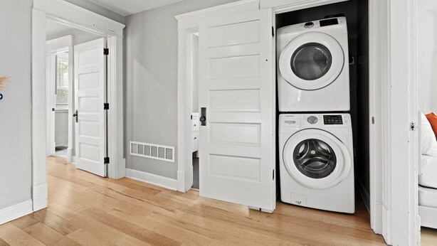 A laundry room with two stacked washers and dryers, wooden flooring, and white doors.
