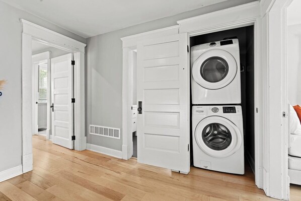 A laundry room with two stacked washers and dryers, wooden flooring, and white doors.