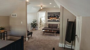 A spacious living area with a high ceiling, a sofa, a coffee table, and a painting on the wall.