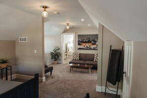 A spacious living area with a high ceiling, a sofa, a coffee table, and a painting on the wall.