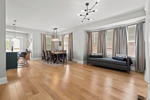A spacious living area with a dining table, chairs, a sofa, and a chandelier. - Streetcar Central - Hyde Park Home in Midtown KC (Kansas City)