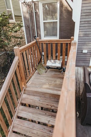 Eine Holzterrasse mit einem Metallgrill und einem kleinen Tisch.