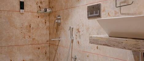 Un bagno moderno con un water sospeso, zona doccia e lavabo con piano in marmo.