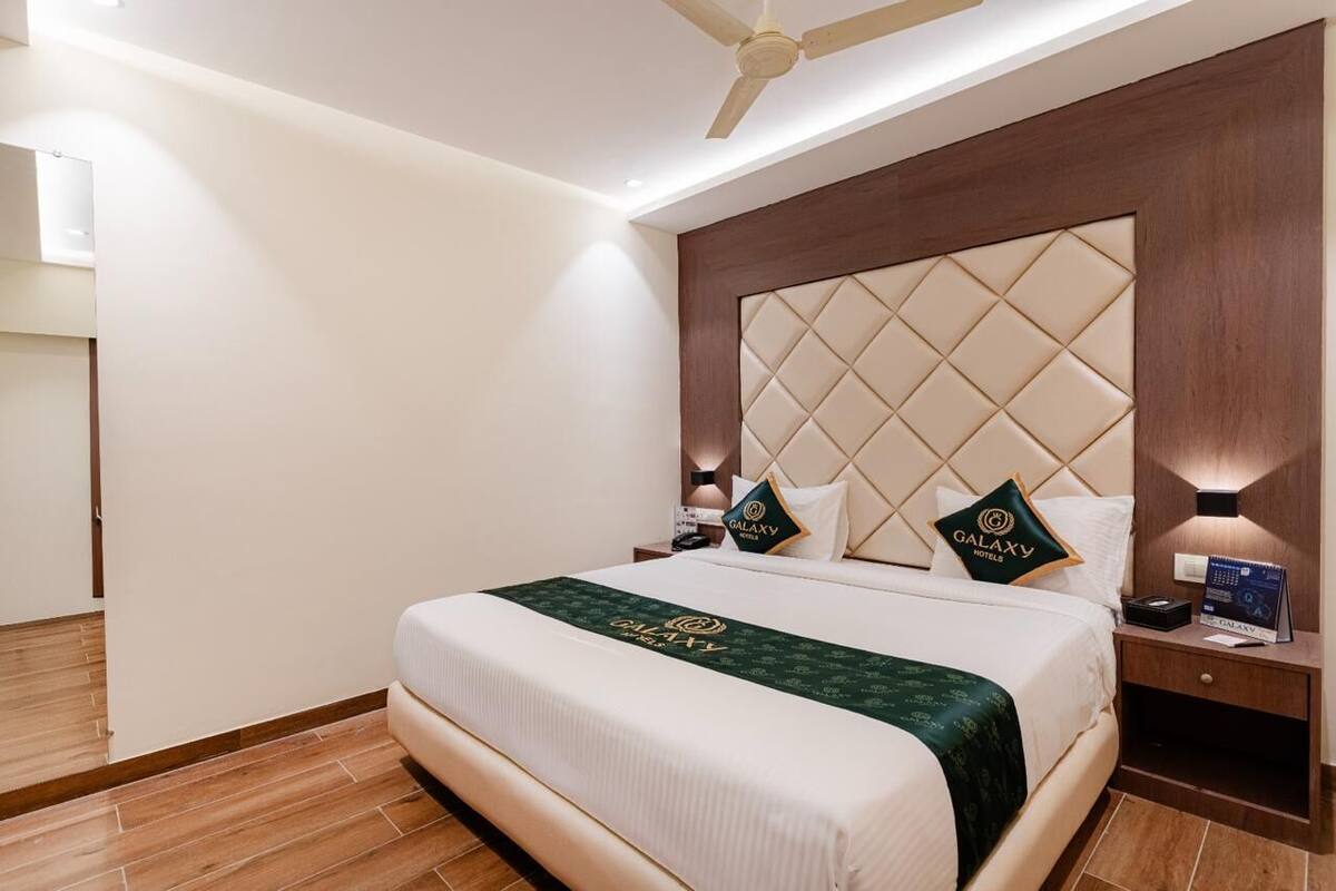A hotel room with a large bed, a ceiling fan, and a nightstand with a lamp.