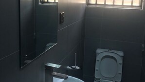 Et lille badeværelse med vask, toilet og spejl.