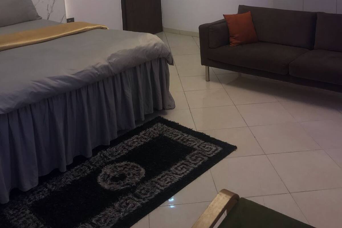 A bedroom with a bed, a sofa, a wardrobe, and a door.