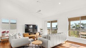 A modern living room with a grey sofa, wooden coffee table, and a flat-screen TV.